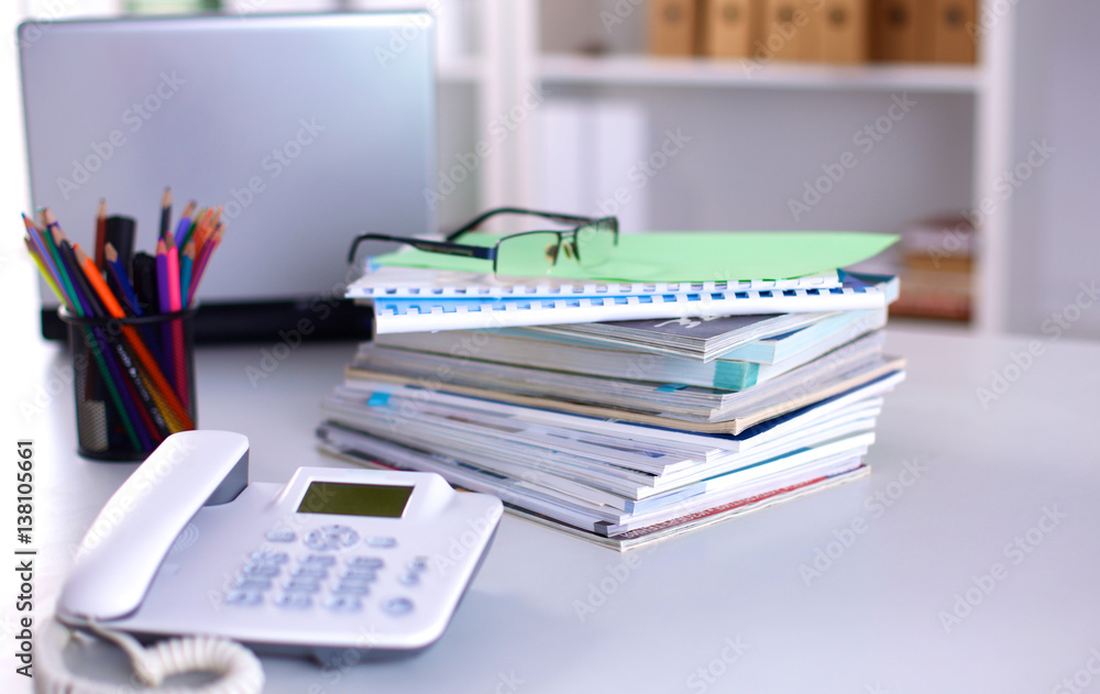 A note book, laptop, pen, graph paper document on the office desk table behind white blind A note book, laptop, pen, graph paper document on the office desk table behind white blind