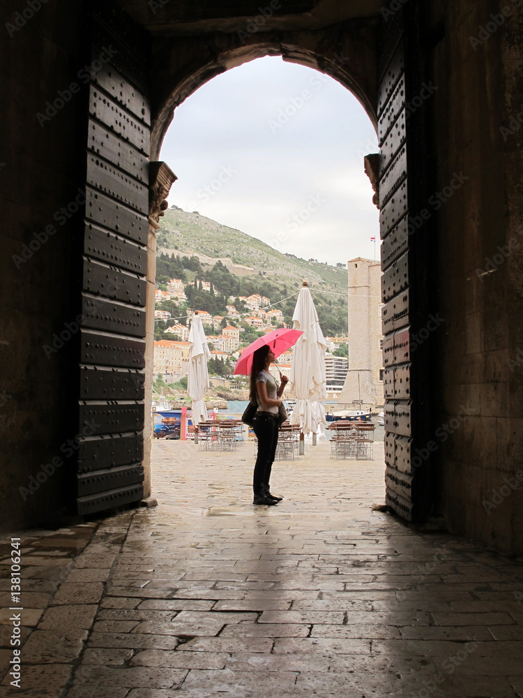 woman holding a pink umbrella at Dubrovnick streets in Croatia