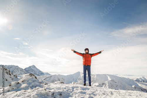 Man on the top of the world raised his hands proud of his achievements