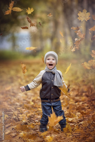 Little boy and yellow leaves of autumn