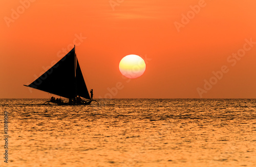 Traditional sailing boat and a tropical sunset on a calm ocean