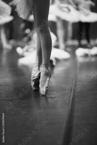 Elegant legs of a ballerina standing on pointe on stage during rehearsal
