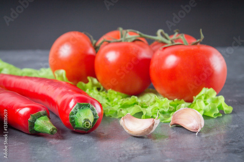 chili peppers, tomatoes, lettuce, garlic on a gray background.