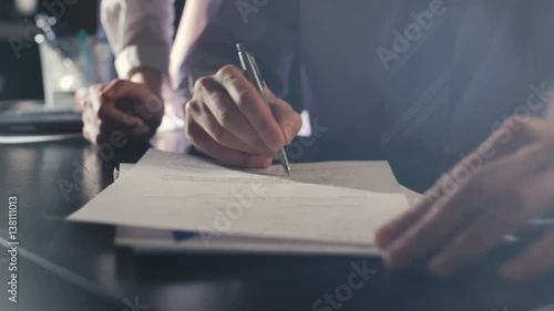 Close-up of male hands with pen over document