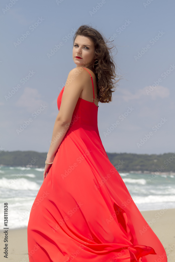 Portrait of beautiful woman in red dress in front of the beach. Portrait of beautiful woman in red dress in front of the beach.