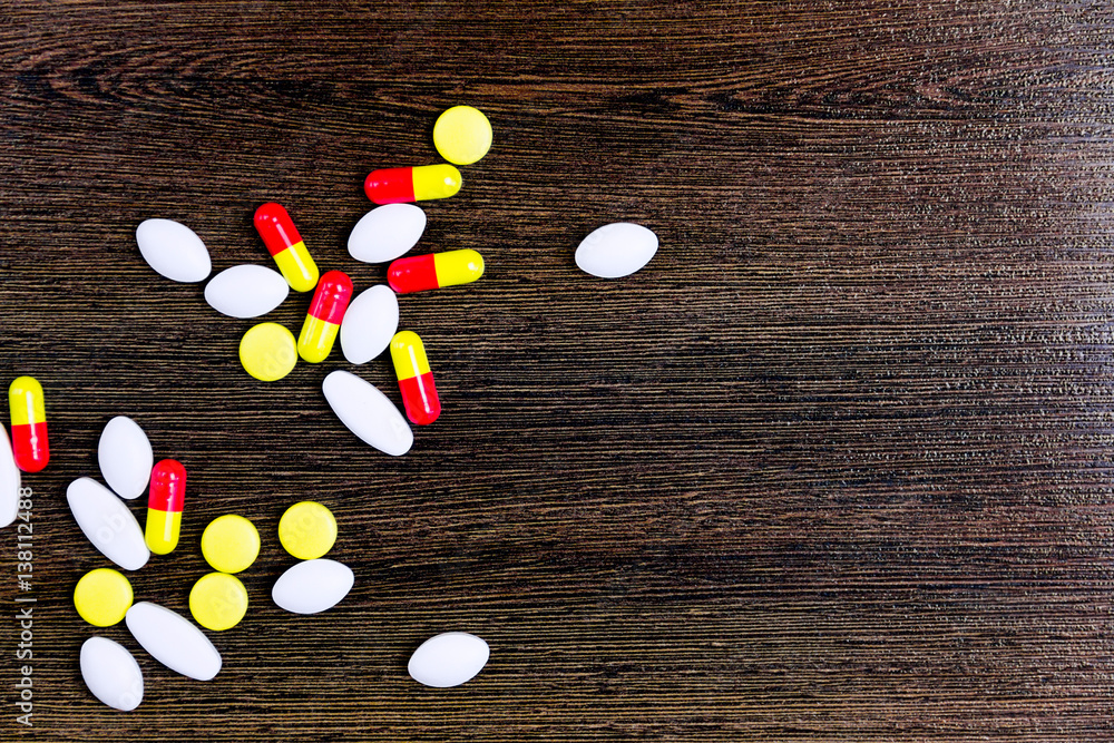 Colorful pills isolated on wooden background