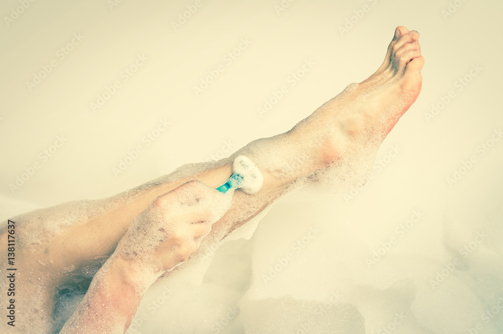 Fototapeta premium Woman shaving legs with razor in bathroom