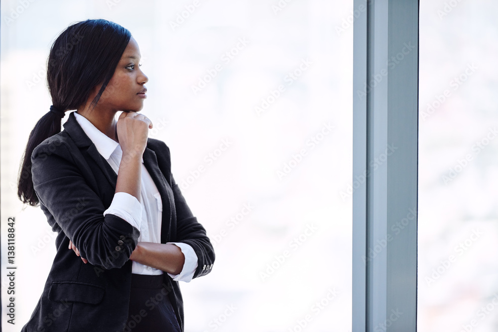 African busineswoman wearing black looking out windowwhile thinking about her future investments that need to be grown for her retirement to allow her financial security. African busineswoman wearing black looking out windowwhile thinking about her future investments that need to be grown for her retirement to allow her financial security.