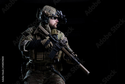 Spec ops soldier SWAT/Special Forces soldier in helmet with night vision device and rifle on dark background