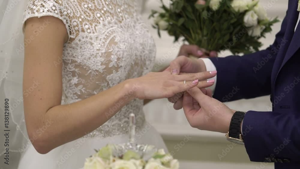 Groom puts on ring to bride's hand on wedding ceremony Groom puts on ring to bride's hand on wedding ceremony