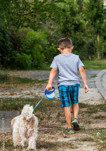 child walking his dog on a leash in countryside photo