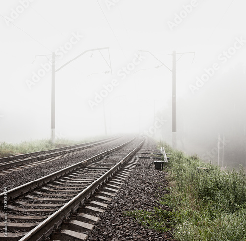 Railway in Fog. Misty Morning Landscape. Empty Railroad. Toned and Filtered Photo with Copy Space. Mystical Nature Background.