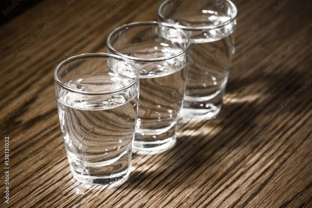 Vodka shots filled with alcohol on wooden bar. Vodka shots filled with alcohol on wooden bar.