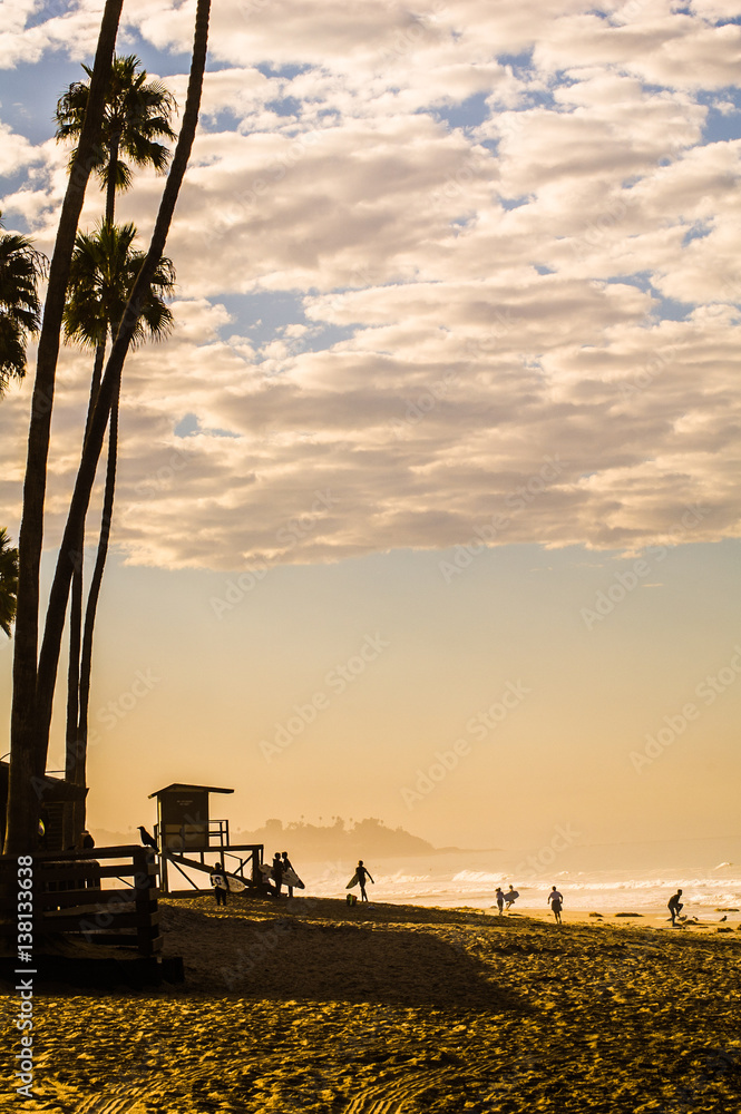 Surfers on California beach at sunset