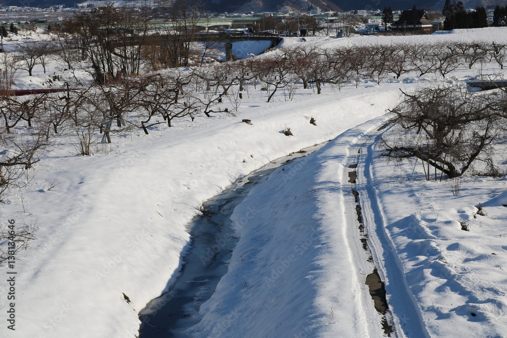 雪の田舎風景/雪に埋もれる田舎の川辺の風景