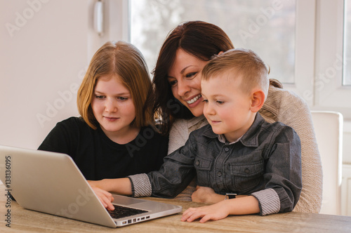 Mother with kids watching cartoons on computer at home