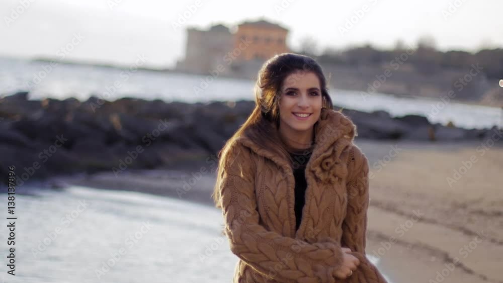Happy fashion female model playing with long hair looking camera in front of the ocean Happy fashion female model playing with long hair looking camera in front of the ocean