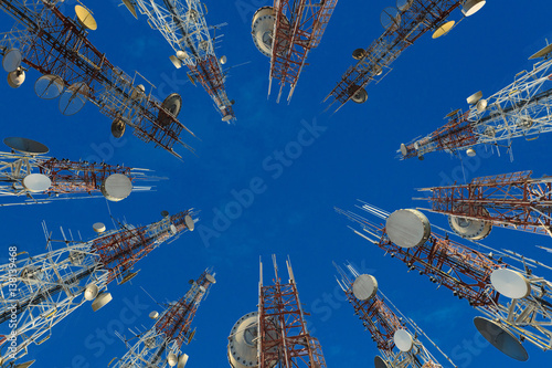 Mobile phone communication antenna tower with cloud and blue sky.