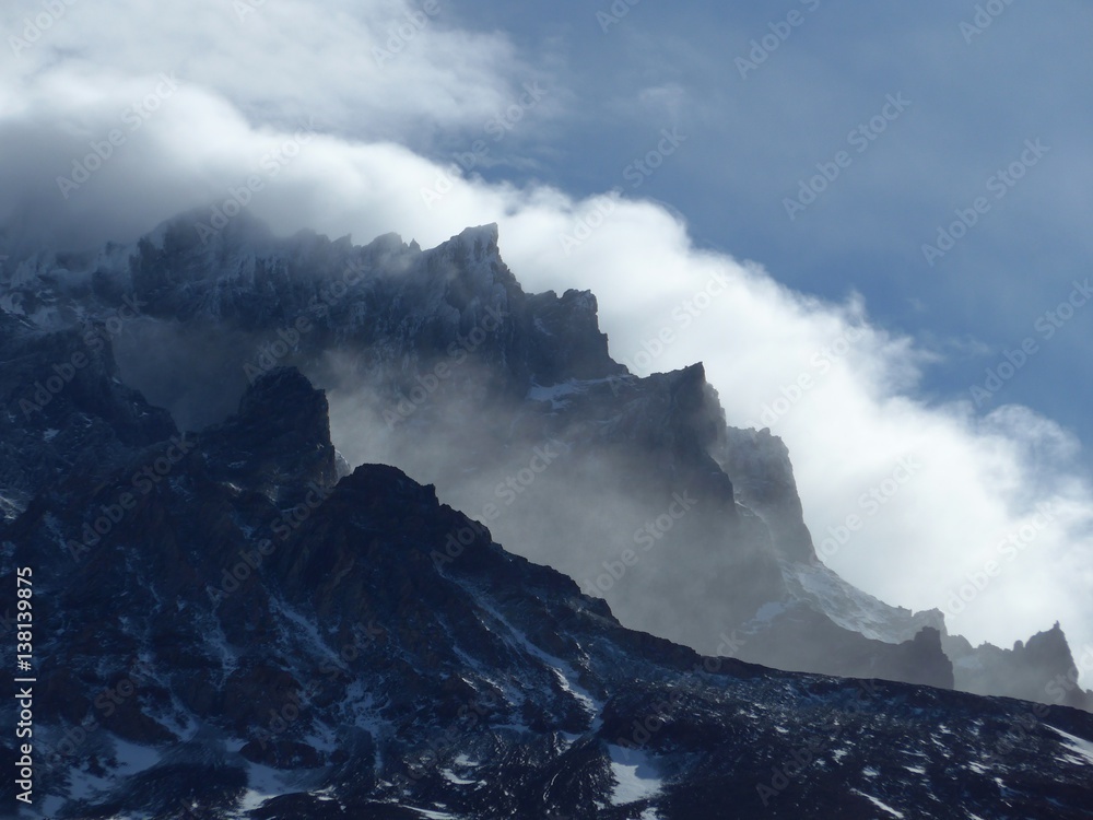 Clouds swirling around the peaks of large towers in the strong Patagonia winds in Torres del Paine National Park. 