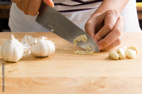 Photography Woman chopping garlic on wooden board for cooking