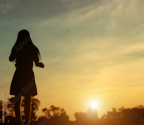 Silhouette of woman praying over beautiful sky sunset background