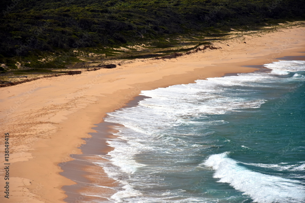 View of coastline of Australia. Waves reach the sandy bank.