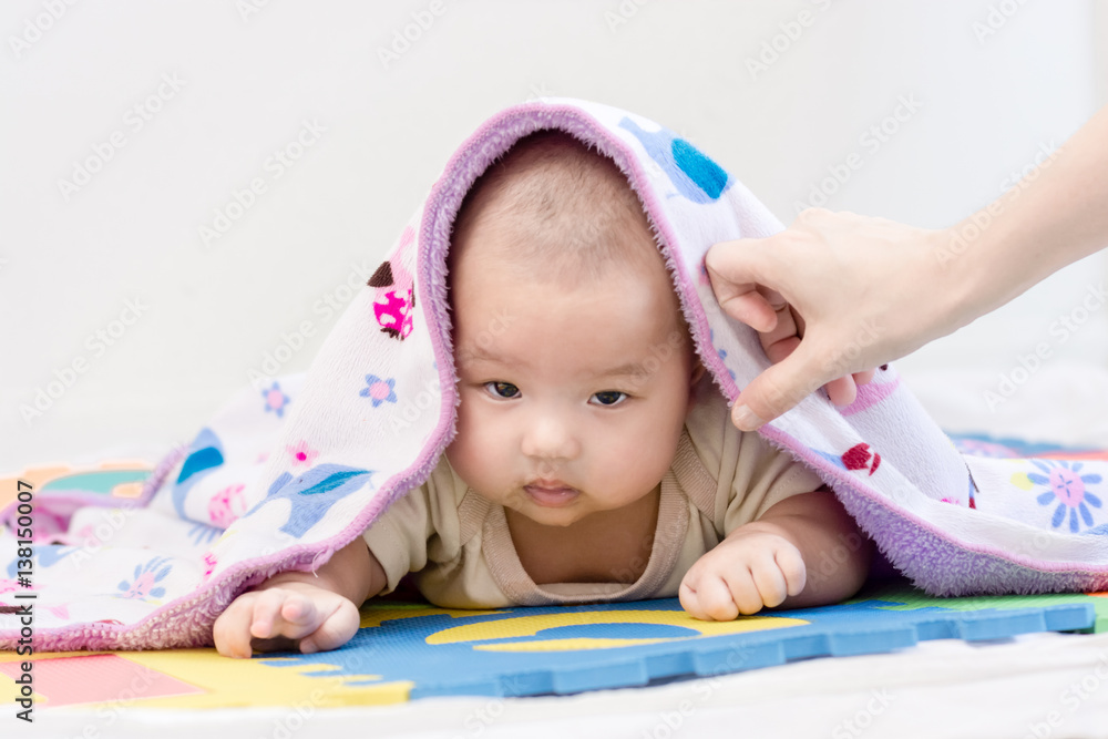 Portrait of a little adorable infant baby girl with blanket and saliva lying on the tummy on colorful eva foam and looking forward indoors Portrait of a little adorable infant baby girl with blanket and saliva lying on the tummy on colorful eva foam and looking forward indoors