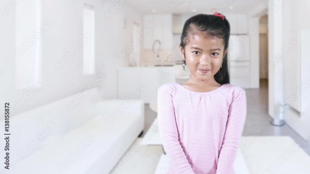 Cute little girl standing in the living room, looking at the camera and looks ashamed Cute little girl standing in the living room, looking at the camera and looks ashamed