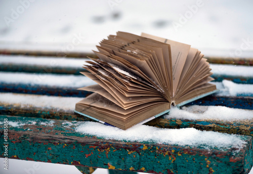 Older interesting book on the street in the winter in the snow. Reading a book in the winter in the snow.