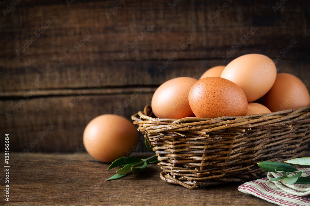 Fresh eggs in a rustic willow basket against dark wooden background Fresh eggs in a rustic willow basket against dark wooden background