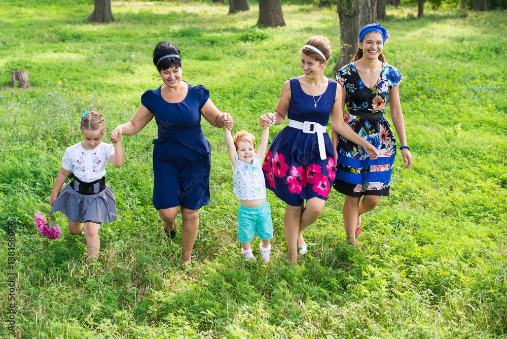 Fototapeta premium Big happy family on a walk in the park. Grandmother, daughter and granddaughter walk in the spring. Women of all ages have fun together 