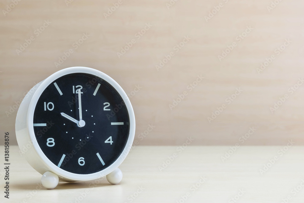 Closeup alarm clock for decorate in 10 o'clock on brown wood desk and wall textured background with copy space Closeup alarm clock for decorate in 10 o'clock on brown wood desk and wall textured background with copy space