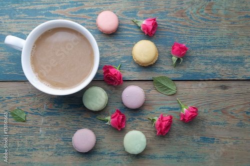 Macaroons, coffee and rose on green wooden background. Top view. Flat lay