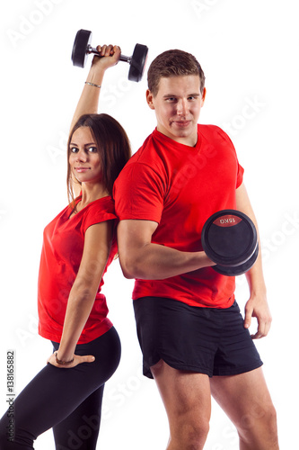 Muscular bodybuilder guy with woman doing exercises with dumbbells over white background