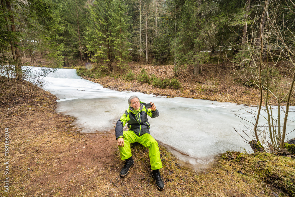Senior taking a selfie near frozen river