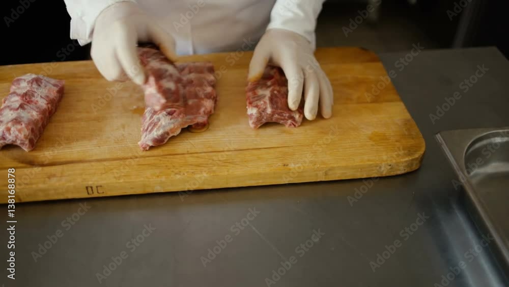 Closeup of professional chef prepare meat ribs on cutting board at restaurant kitchen Closeup of professional chef prepare meat ribs on cutting board at restaurant kitchen