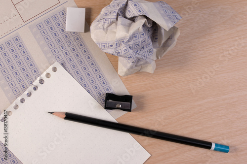 Crumpled paper ball of vintage classic answer sheet with pencil, sharpener and paper reduction. Cross the right answer in the box with blank answer. Answer sheet concept. photo