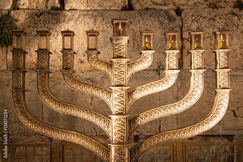 Hanukiah with four candles lit with the wailing wall in background , from the front