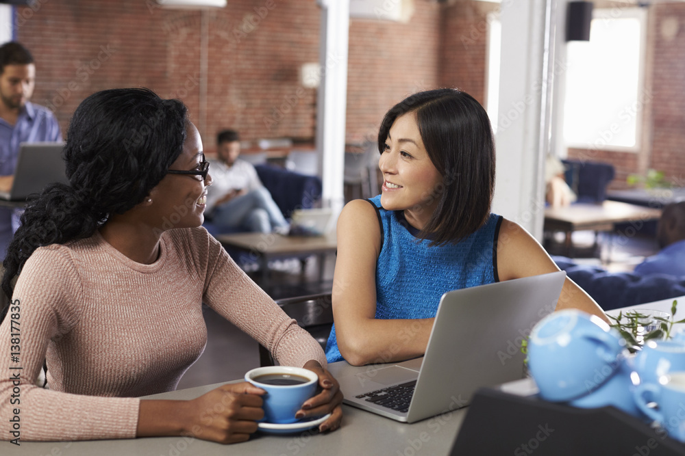 Two Businesswomen Have Informal Meeting In Office Coffee Bar Two Businesswomen Have Informal Meeting In Office Coffee Bar
