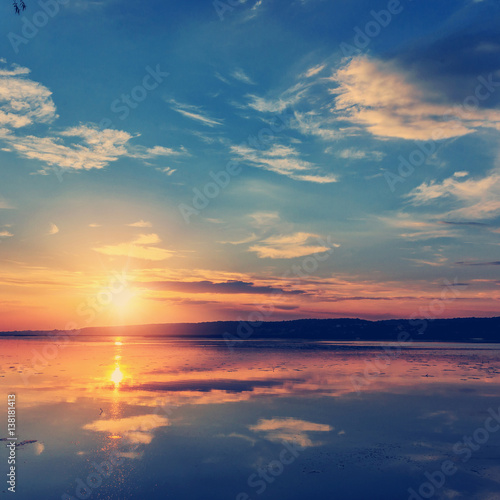 Sunset over the lake. colorful clouds in the sky  reflected in the water. picturesque  dramatic scene.