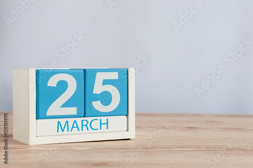 March 25th. Day 25 of month, wooden color calendar on table background. Spring time, empty space for text.