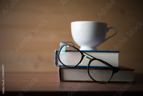 Concept of education - Coffee cup on pile of books with eyeglasses.