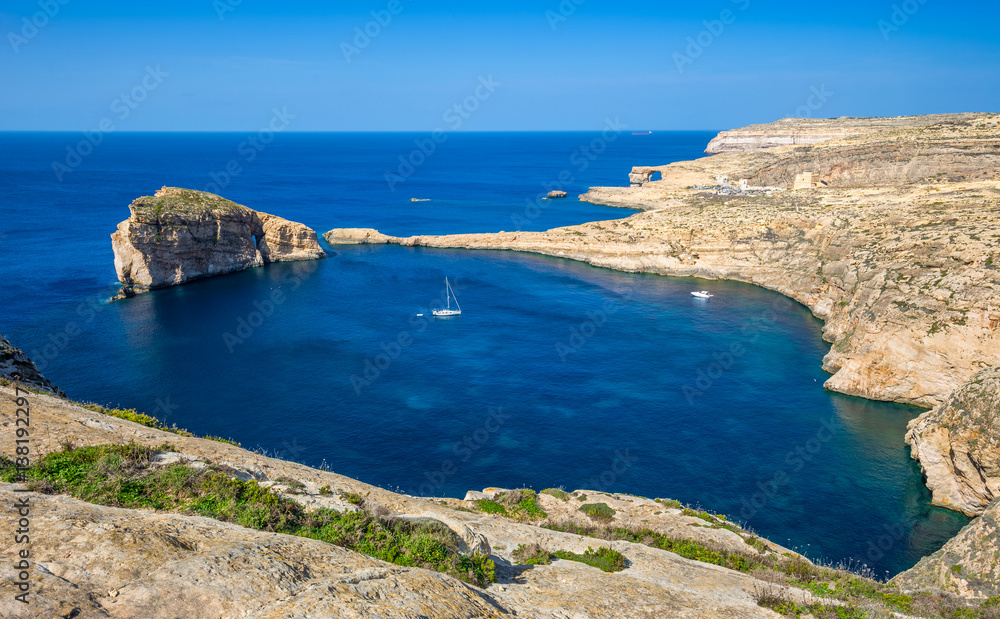 Gozo, Malta - Panoramic skyline view of Dwejra bay with Fungus Rock, Azure Window and sailboat on a nice hot summer day