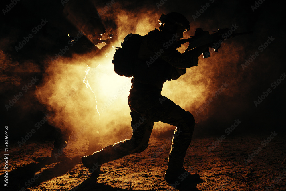 Pair of army soldiers attacking in the smoke. Backlit silhouette, toned image. Army storm concept