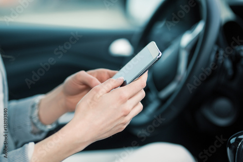 Businesswoman using smart phone in the car.Phone and hands are in focus. © BalanceFormCreative