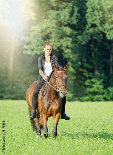 Junge Frau reitet mit ihrem Pferd durch Wald und Flur