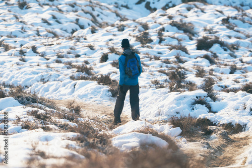 Young man walking in winter landscape.