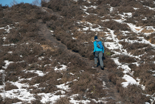 Man walking uphill in winter landscape.