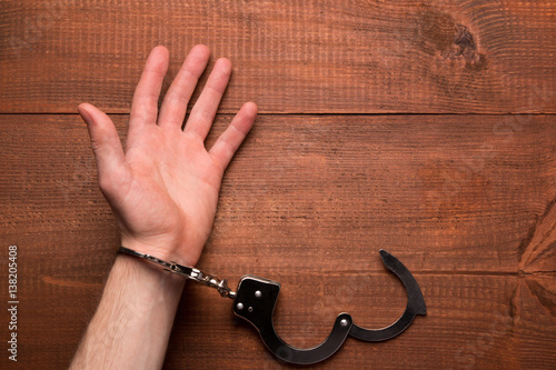 Man hand with handcuffs on the table. photo