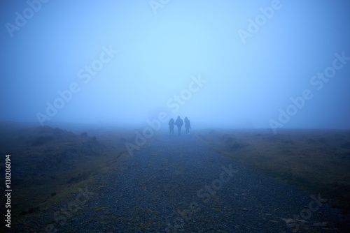 tres personas caminando hacia la niebla